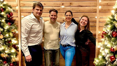 AG Europa wünscht frohe Weihnachten Das Foto zeigt die vier Mitglieder der AG Europa. Rechts und links von der Gruppe steht jeweils ein Weihnachtsbaum.