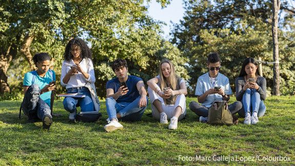 Trendstudie Jugend in Deutschland - dbb jugend sieht neue Regierung in der Bringschuld Group of teenage friends looking at phone in the park on green grass. Three boys and three girls